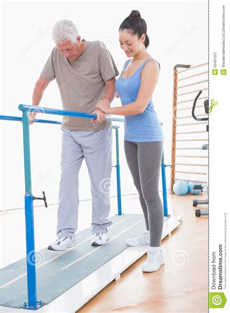Senior Man Walking With Parallel Bars And Coach Help Stock Image