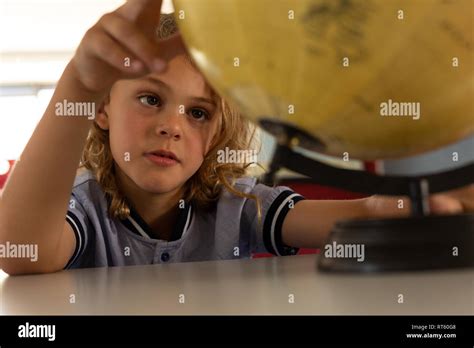 Schoolgirl Studying Globe At Desk In A Classroom Stock Photo Alamy