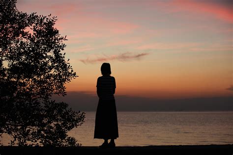 Silhouette Of A Woman Standing Alone At The Seaside During Sunset