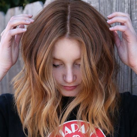 Woman Looking Down And Touching Her Subtle Peachy Blonde Ombre Hair Color Best Ombre Hair