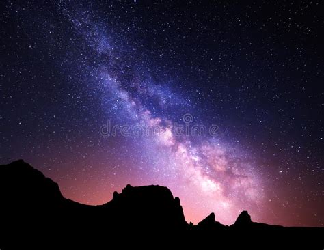 Night Landscape With Colorful Milky Way And Yellow Light At Mountains