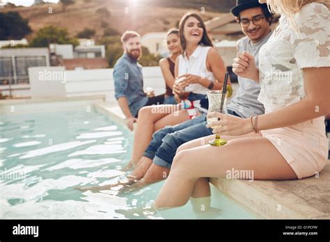Shot Of Young People Drinking Cocktails The Swimming Pool Friends Sitting On The Edge Of The