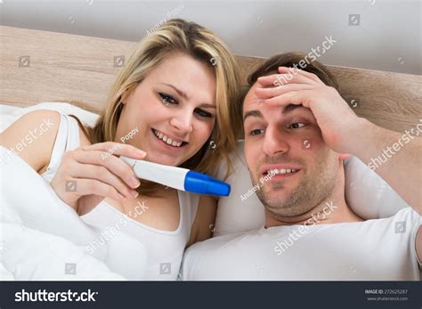 Couple Looking At A Positive Pregnancy Test In Bedroom Stock Photo