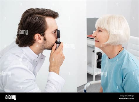 Optometrist Doing Eye Exam To A Patient Using An Ophthalmoscope