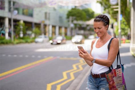 Happy Mature Beautiful Tourist Woman Using Phone In The City Streets