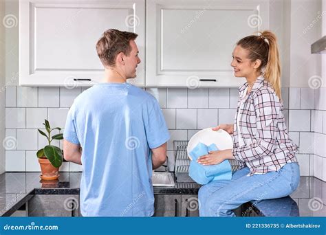 Happy Caucasian Woman Wiping Dishes While Husband Washing At Kitchen
