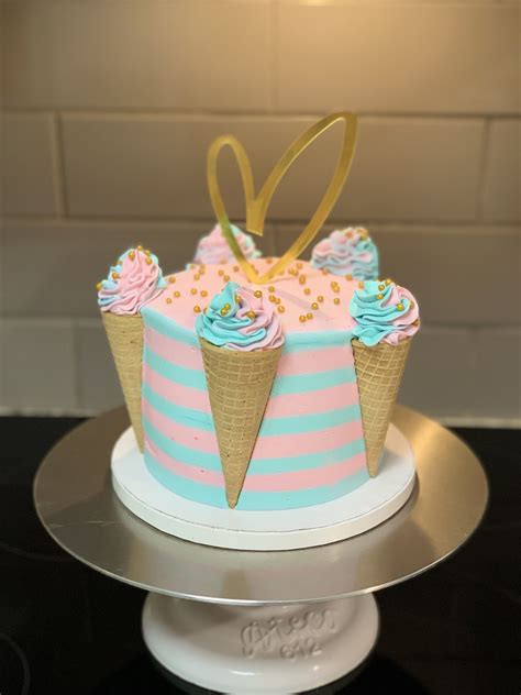A Pink And Blue Cake With Ice Cream Cones On Top