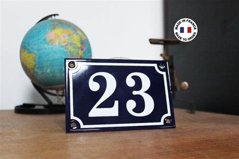 A Small Blue And White House Number Twenty Three On A Wooden Table Next