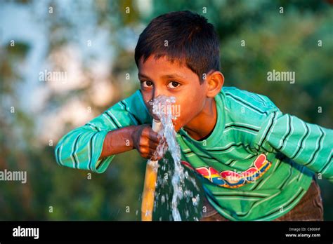 Indian Boy Drinking Water From A Hosepipe Andhra Pradesh India Stock