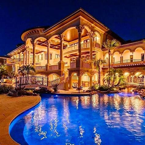 A Large Mansion With A Swimming Pool In Front Of It At Night