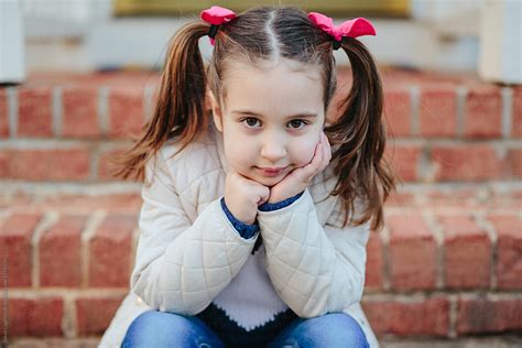 Cute Young Girl In Pigtails Sitting On Steps Looking Bored By Jakob