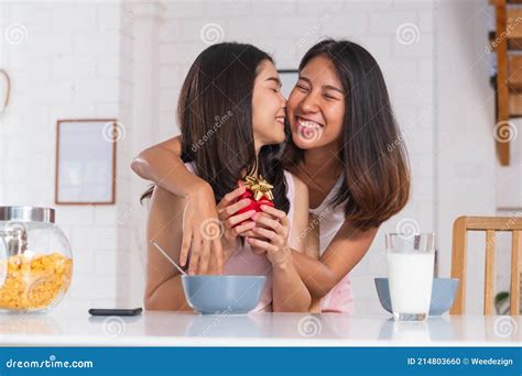 asian lesbian couple surprise by giving t for anniversary of love at kitchen breakfast time