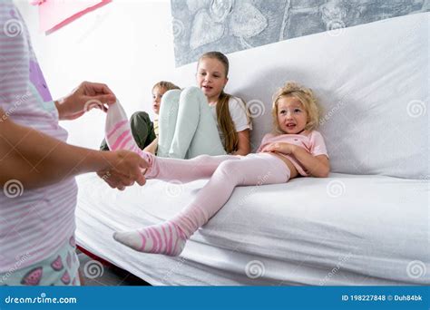 Mom Takes Off Her Little Daughter`s Socks And Tickles Her Feet A Little 680