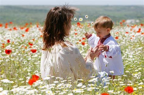 Mother And Son In Traditional Clothes In Flower Field