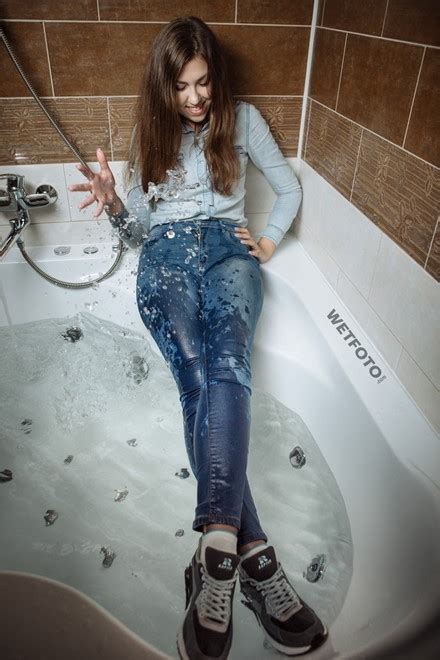 cool brunette in light denim shirt tight jeans and sneakers in jacuzzi
