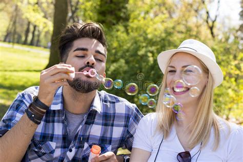 Young Attractive Couple Having Fun While Blowing Bubbles Together On A