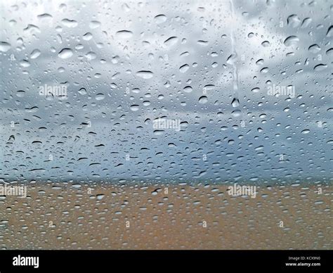 Raindrops On Window With Beach And Stormy Sky Blurred Background Stock