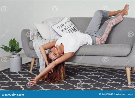 beautiful woman relaxing on a grey couch with head upside down cute girl having fun at cozy