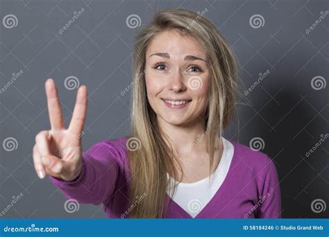 Fun 20s Woman Showing A Victory Or Peace Sign Foreground Stock Photo