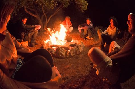 Group Gathered Around Campfire In The Woods Stock Photo Download