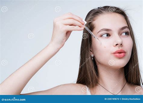 une jeune fille séduisante se débarrasse des imperfections en appliquant du sérum sur son visage