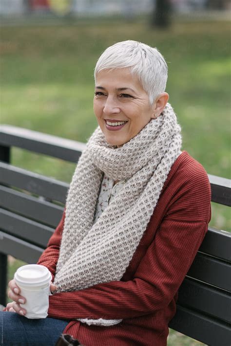Smiling Senior Woman Sitting On The Park Bench By Stocksy Contributor