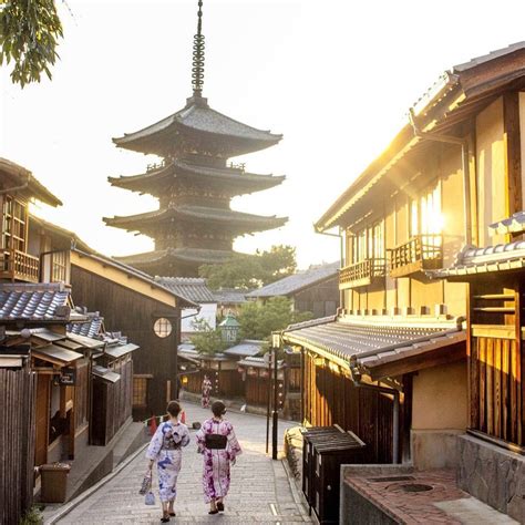 Two Women In Kimonos Walking Down An Alley Way With Pagodas In The Background