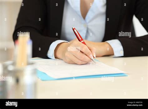 Close Up Front View Of An Office Worker Hands Filling Form On A Desktop