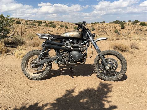 Such bikes were fitted with rugged knobby tyres, high travel suspension, engine protectors and reinforced spoked wheels to withstand the untamed terrains. Triumph Scrambler Desert Sled by Modulus Creative - BikeBound