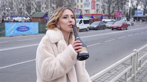 Drunk Woman On A Street Drinks Wine From A Bottle Autumn Day Stock