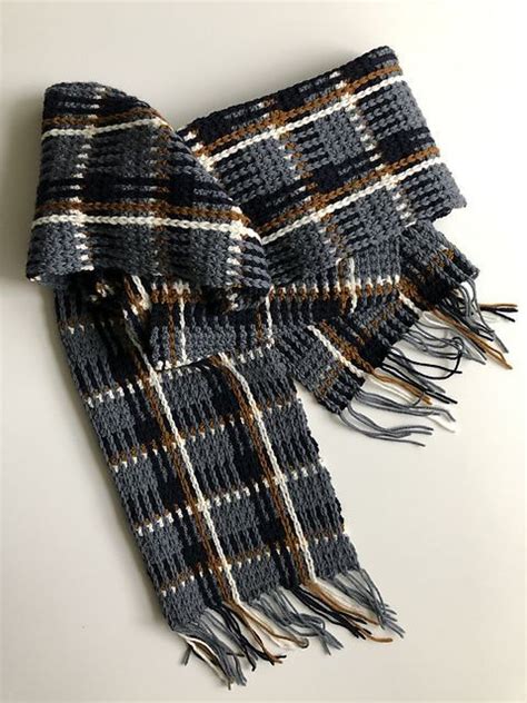 A Black And White Plaid Scarf Laying On Top Of A Table