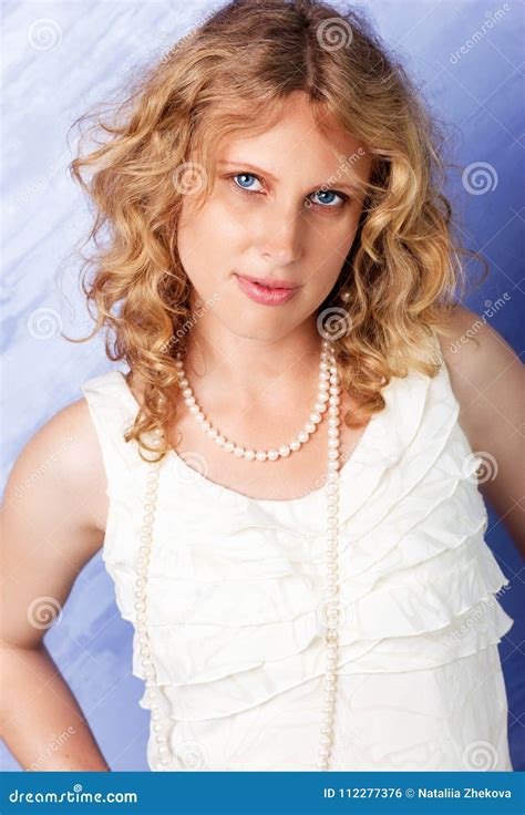 blonde rizado de ojos azules hermoso delante del fondo azul foto de archivo imagen de