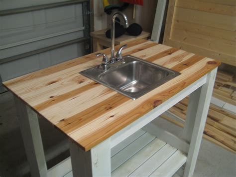 A Kitchen Island Made Out Of Pallet Wood With A Sink And Faucet