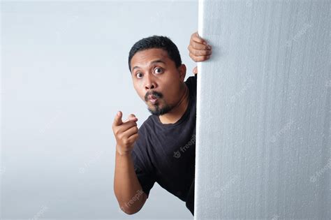 Premium Photo Man Peeking Behind Wall While Pointing Finger