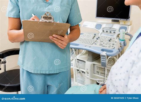 Nurse Writing On Clipboard With Patient In Stock Image Image Of