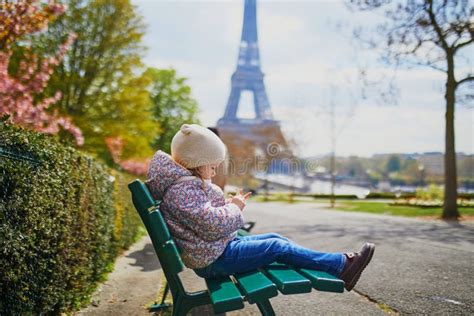 Adorable Three Year Old Girl Sitting On The Bench Near The Eiffel Tower In Paris France Stock