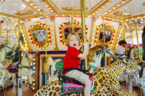 Boy Riding A Carousel At An Amusement Park Stock Photo Offset