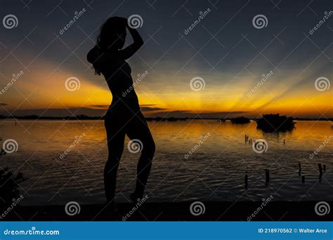 A Lovely Nude Latin Model Is Silhouetted As She Poses With The Rising Sun Behind Her On A