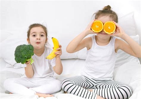 Premium Photo Happy Two Cute Girls Eating Fruits And Vegetables In