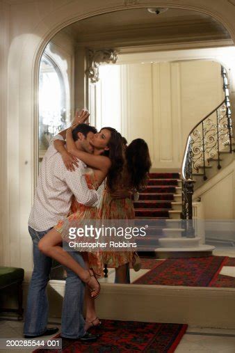 Couple Embracing Against Mirror In Foyer Man Kissing Womans Neck Photo