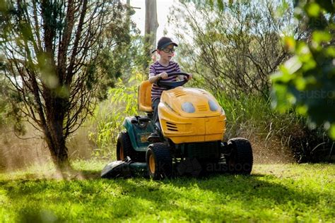 Image Of Boy Mowing The Front Yard On A Ride On Lawn Mower Austockphoto