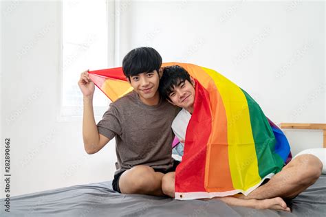 Portrait Of Asian Gay Couple Smiling On Face Looking At Camera Covering Body By Rainbow Flag