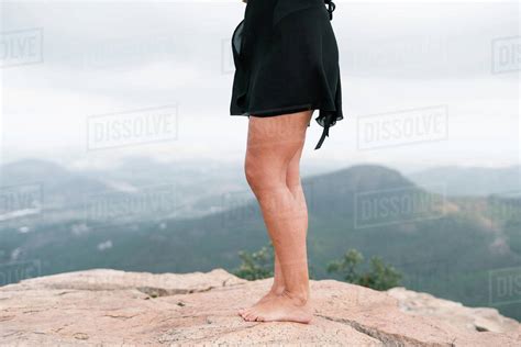 Side View Of Anonymous Barefoot Female In Black Skirt Standing On Rough