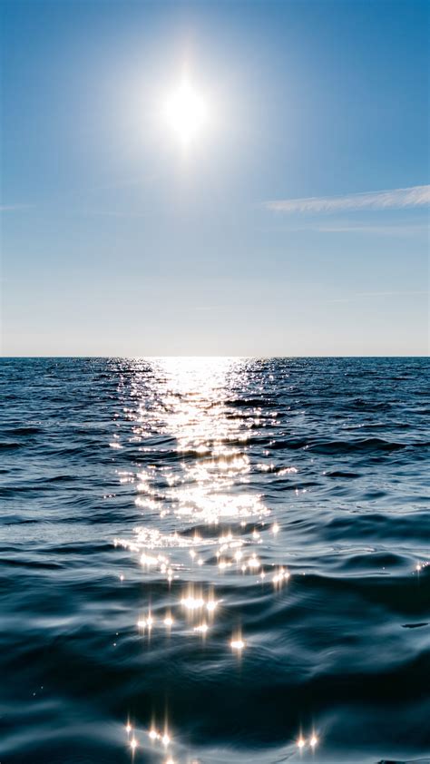 Download Wallpaper Sun On Blue Sky Is Reflected On Water 1080x1920