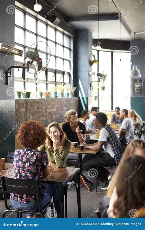 Interior Of Busy Coffee Shop With Customers Sitting At Tables Stock