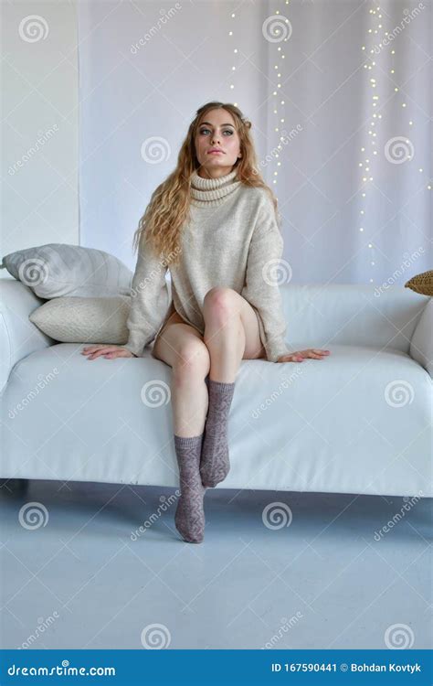 Girl Sits In Erotic Poses With Legs Wide Apart On Sofa In Sweaters And Socks And In Black