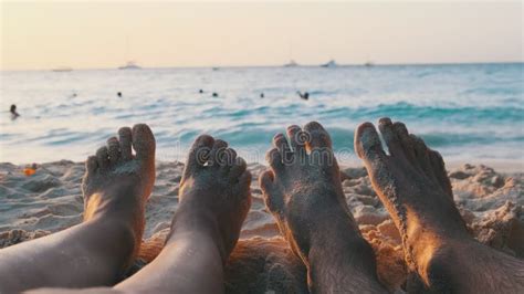 Pov Feet Of A Couple Of Men And Women Lying On A Sandy Beach At Sunset