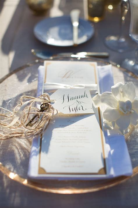 The Table Is Set With White And Gold Place Settings