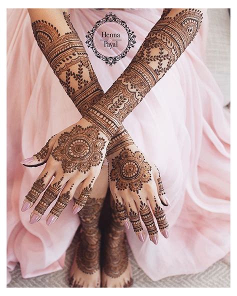 A Woman With Henna Tattoos On Her Hands And Legs Sitting In A Pink Dress