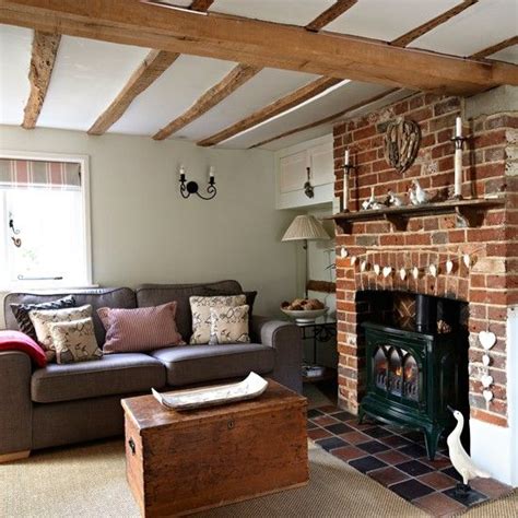 Unique home stays inspiration for a medium sized country formal enclosed living room in other with grey walls, light hardwood flooring, a wood burning stove, a wall mounted tv, beige floors and a metal fireplace surround. Country living room with wooden beams and exposed brick ...